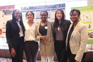Five students pose by the poster describing their research.