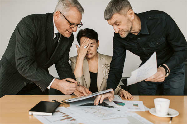 Two men discussing projects with a frustrated female.