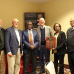 A group of six people hold an award plaque.