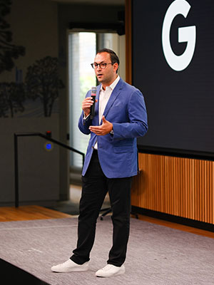 Chris Marino standing on a stage and speaking into a microphone.