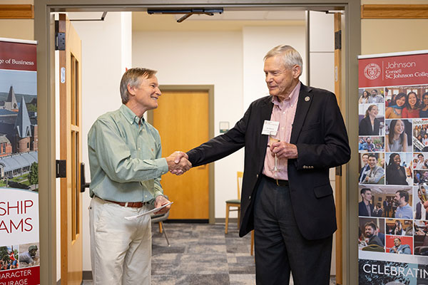 Scott Stewart shaking hands with Joe Thomas at the entrance to the Scott Stewart shaking hands with Joe Thomas at the dedication of the L. Joseph Thomas Diversity, Inclusion, and Leadership Suite.