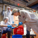 Image of Rebecca Phillips, left, a regional dairy processing specialist with Cornell Dairy Foods Extension, helps John and Sammi Collins bottle their new high-protein chocolate milk drink in Cornell’s Food Processing and Development Laboratory.