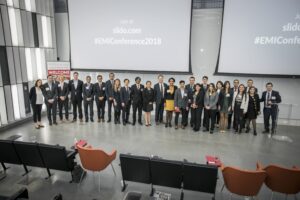 Case competition organizers and participants stand in front of the presentation panels