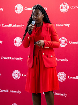 A woman standing on a stage in front of an audience and speaking into a microphone.