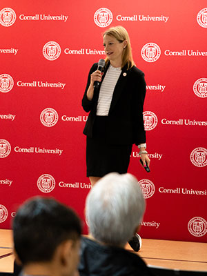 A woman standing on a stage in front of an audience and speaking into a microphone.