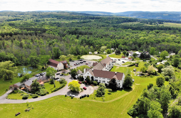 An ariel drone photo of the La Tourelle property, with multiple buildings surrounded by forested rolling hills.