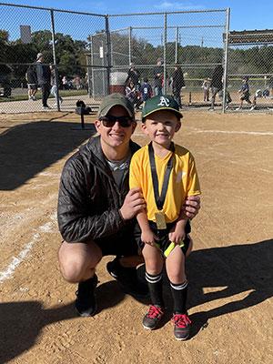 Shawn Driver crouching down next to a small boy on a baseball field.