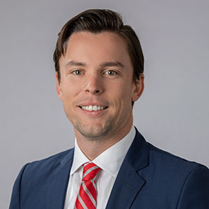 headshot of Zach Sabadosa in a suit and tie.