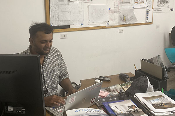 Guru Bhardwaj sitting at a desk, working on a laptop.