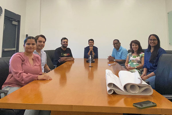 Picture of Guru Bhardwaj and 6 others (3 women and 3 men) sitting at a conference table.