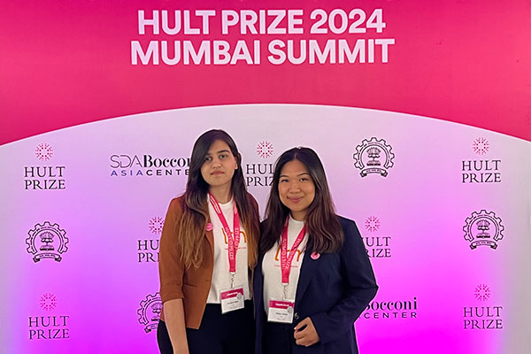 Two women standing side by side in front of a backdrop with the text: Hult Prize and SDA Bocconi Asia Center.