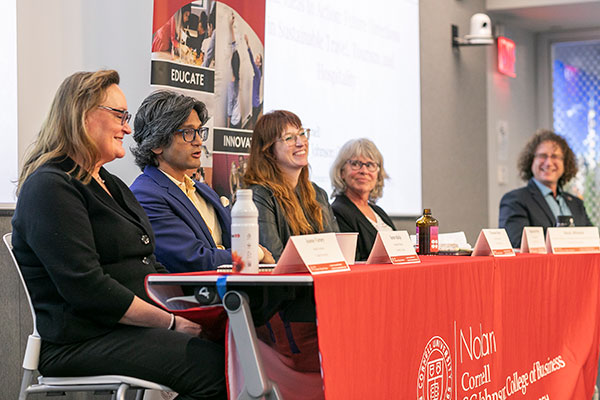 Three women and two men seated at the front of a room at a table draped with an SC Johnson College of Business banner.