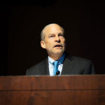 A man standing behind a podium and speaking.