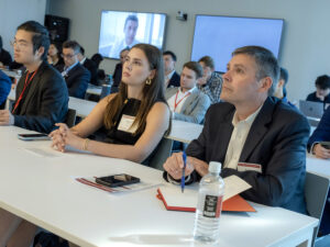 People sit listening to conference presentations.