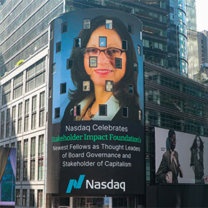 A woman’s face on the NASDAQ jumbotron in Times Square with the text: “NASDAQ celebrates Stakeholder Impact Foundation’s newest fellows as thought leaders of board governance and stakeholder of capitalism.”