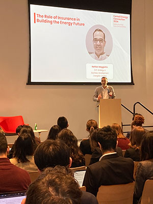 A man standing at a podium on stage and speaking to a large room of people.