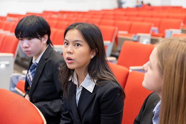 A woman sitting in a classroom with other students seated on either side of her.