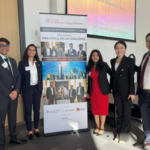 Cornell MBA students posing by an event banner