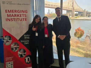 Ashmi Jha, Professor Lailani Alcantara, and Makareem Asser next to the EMI Conference banner; the Queensboro bridge is in the background.