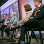 Photo of four panelists on stage at the Cornell Business Forum