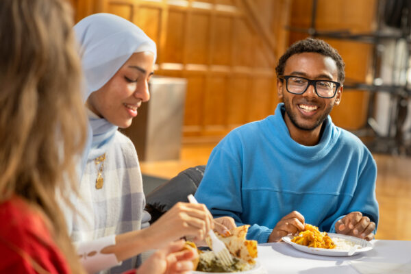 Students wear blue reflective vests and serve warm food and beverages outside.