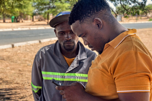 Image of two black men looking for information in a cell phone