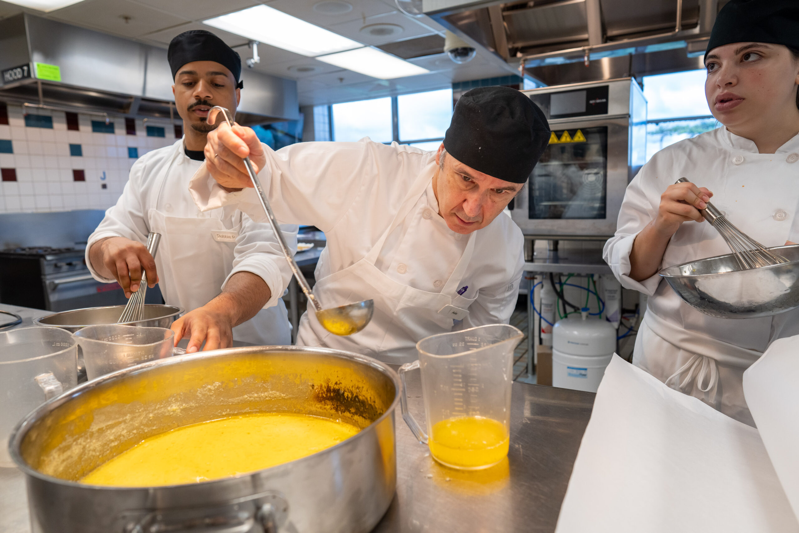 Asís Martínez-Jerez works on a hollandaise with Robbie Pollock ’23 in the culinary lab for Food Service Management, Theory, and Practice.