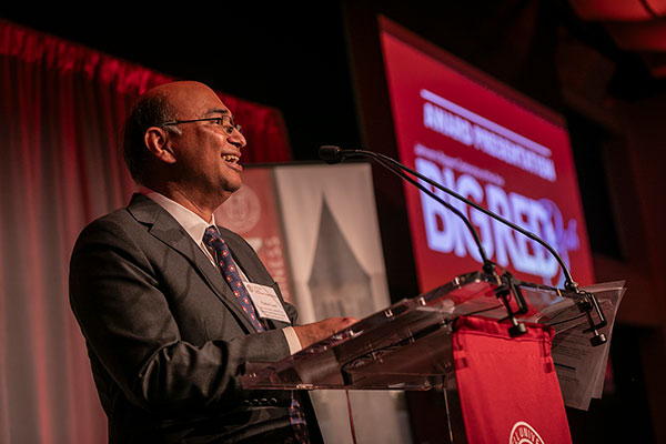 Vishal Gaur standing at a podium on stage and smiling.
