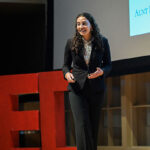 A woman dressed in business attire speaking on stage.