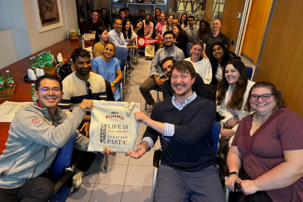 Image of a large group of students gathered together with a Cornell banner during the Rummo-Cornell Family Business Trek