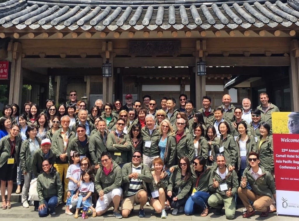 Group of people in green jackets smile together at the camera.