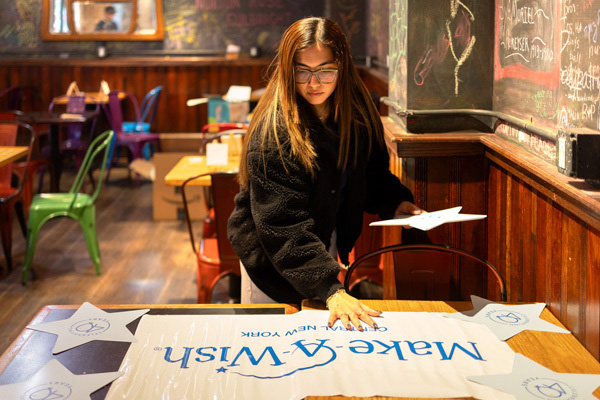 Image of female student setting up for a “Paint and Sip” event at Collegetown Bagels in Ithaca, to raise money for Make-A-Wish Central New York.
