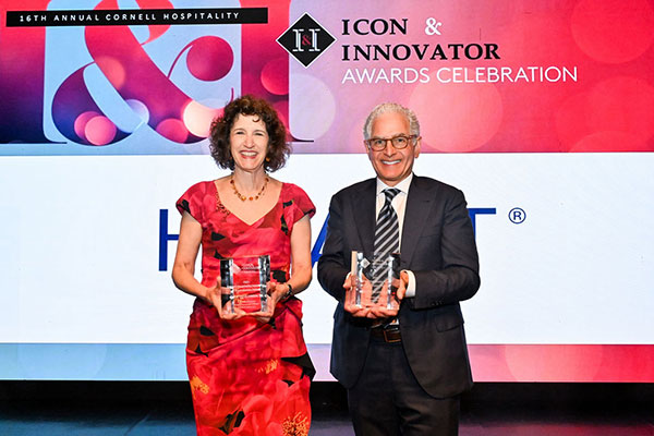 a woman and a man standing next to each other, holding crystal awards and smiling.