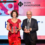 a woman and a man standing next to each other, holding crystal awards and smiling.