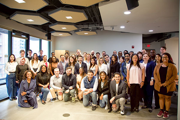A group of 20-30 young adults posing for a photo in a large room.