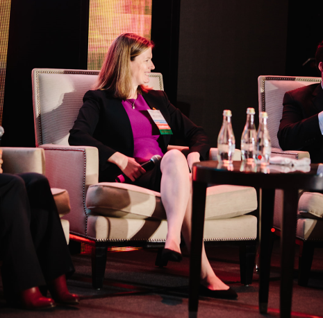 Britta speaking on stage during a panel presentation at a conference
