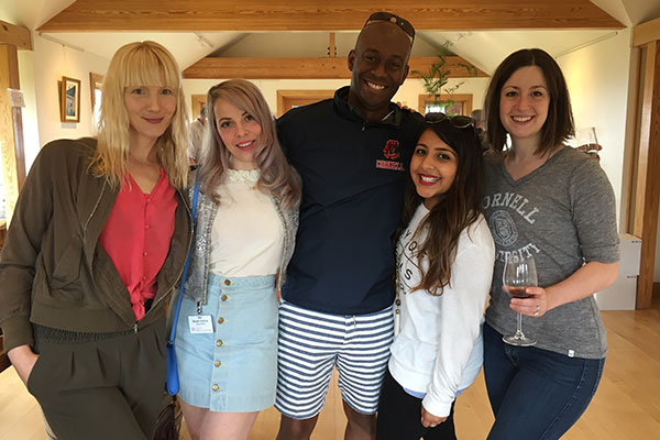 Four women and one man posing with arms around one another and smiling at the camera.