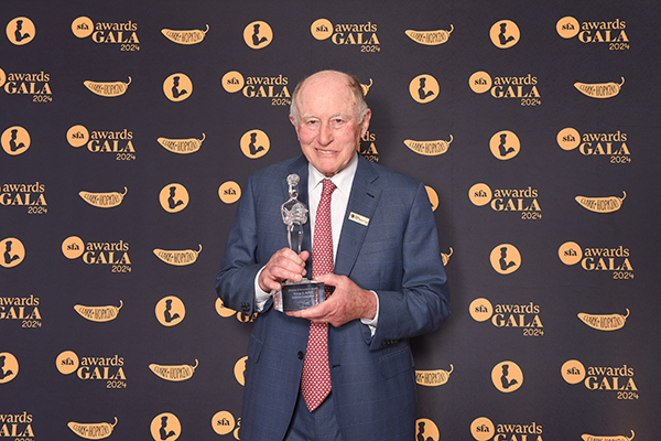 George Gellert in front of a background holding his award