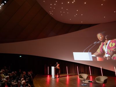 Esohe Denise Odaro on stage, speaking in front of a crowd as a conference keynote speaker