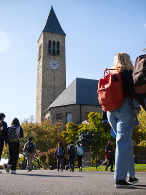 Cornell students walking in front on Clock Tower on Cornell campus