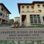 Vanessa Purnawan MBA ’26 standing in front of the Stanford Graduate School of Business sign at the Knight Management Center