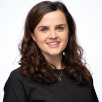 Professional headshot of Zara de Belder smiling and standing behind a white background.