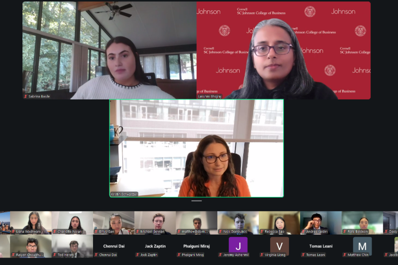 A computer screen depicting a Zoom meeting with three speakers occupying a large portion of the screen and a portion of the audience represented in two rows of participants appearing along the bottom of the screen.