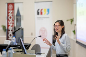 Photo of Simone Tang at a lectern with hands outstretched.