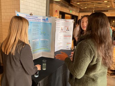 Prerana Reddy and Colby Snyder stand in front of their poster discussing the project details with another student.