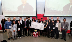 A group of participants and organizers hold a award winning check in the center of the stage