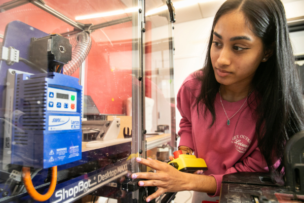 A woman leans in to work with a piece of equipment.
