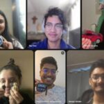 A group of six people smiling during a virtual meeting; each person is holding up an object