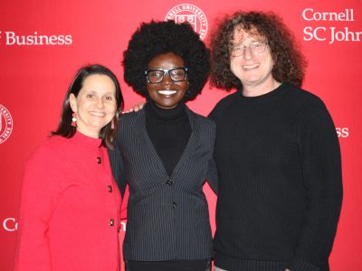 Lydiah Bosire standing with Monica Touesnard and Mark Milstein in front of an SC Johnson College of Business Banner