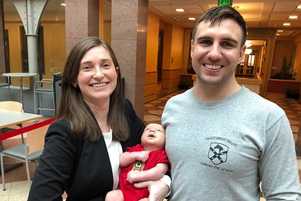 Shannon Boyle holding her child with her spouse at Sage Hall.